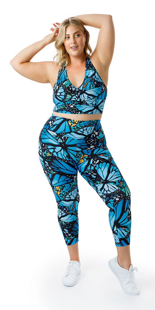 Full body front view of girl in blue animal print JH Butterfly Ultra High Waist 7/8 Leggings and matching bra putting both hands to the back of her head
