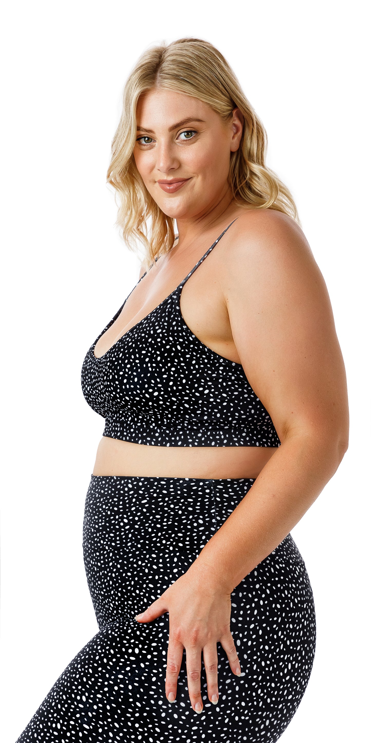 Side view of lady in black Star Dust Momentum Bra and matching bottoms looking at the camera and putting one hand on lap