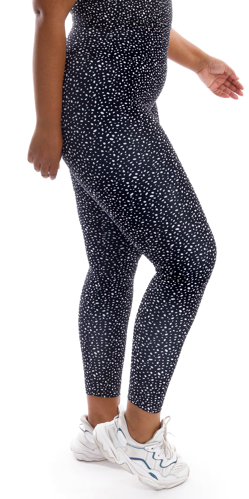 Side view bottom part of girl wearing black Star Dust Body Luxe Ultra High Waist Leggings and white shoes lifting right heel