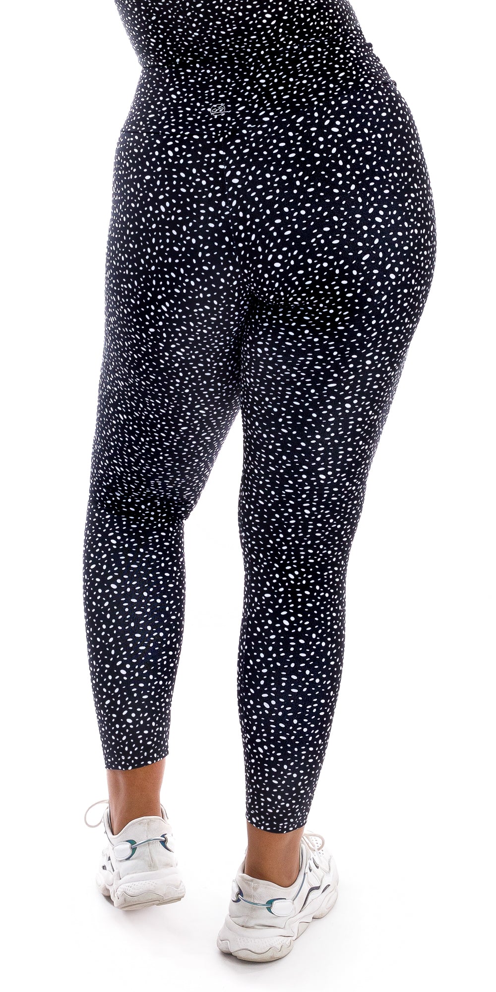 Rear view bottom part of girl wearing black Star Dust Body Luxe Ultra High Waist Leggings and white shoes putting left leg forward