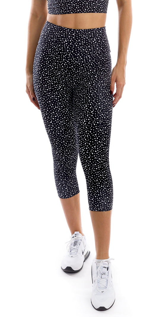 Front view bottom part of girl in black Star Dust Body Luxe Capri Leggings putting left leg forward