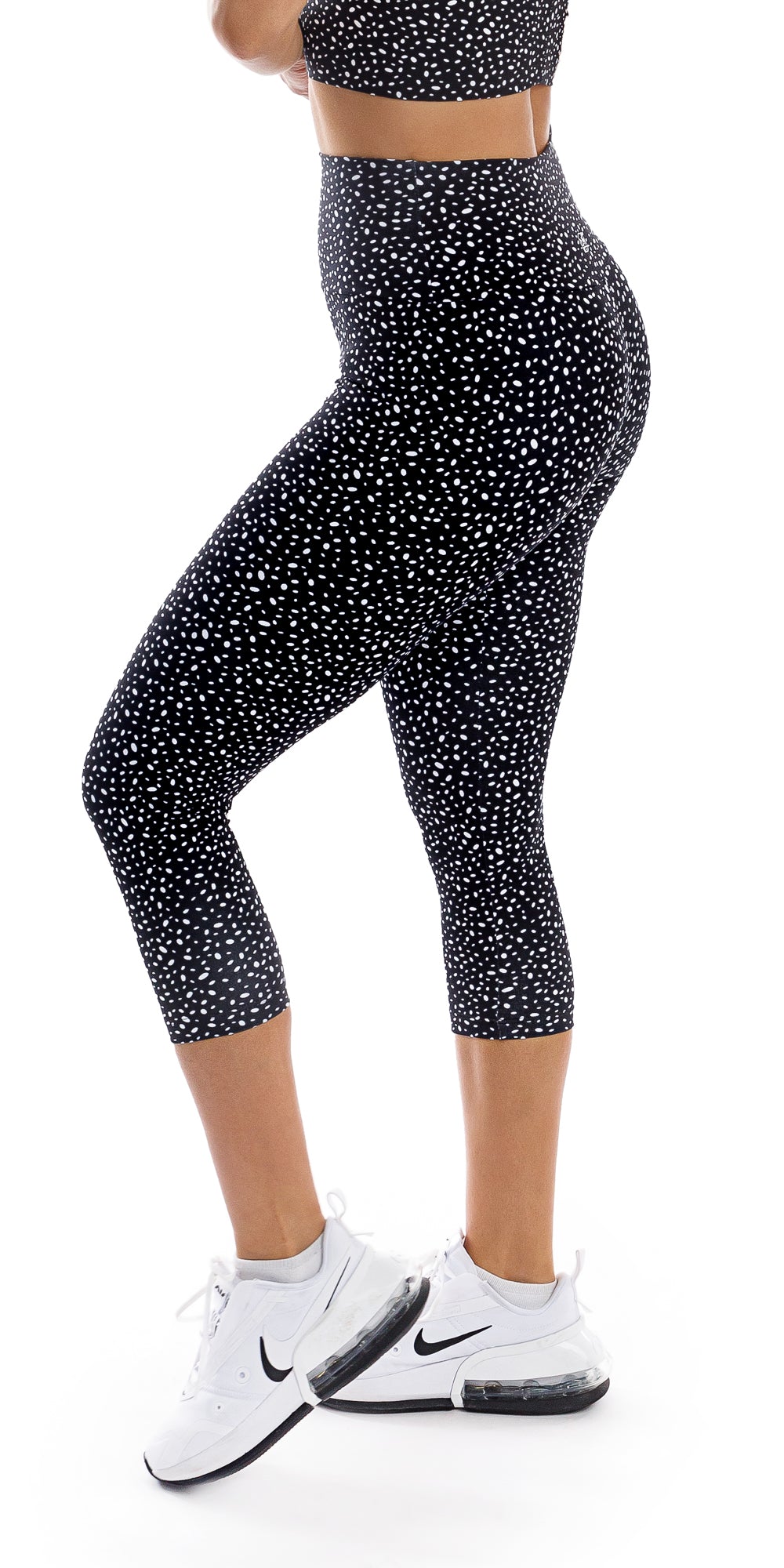 Side view bottom part of girl in black Star Dust Body Luxe Capri Leggings lifting left heel