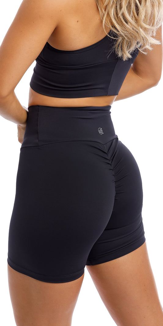 Rear view of girl wearing midnight body luxe scrunch bum midi shorts & matching racer bra