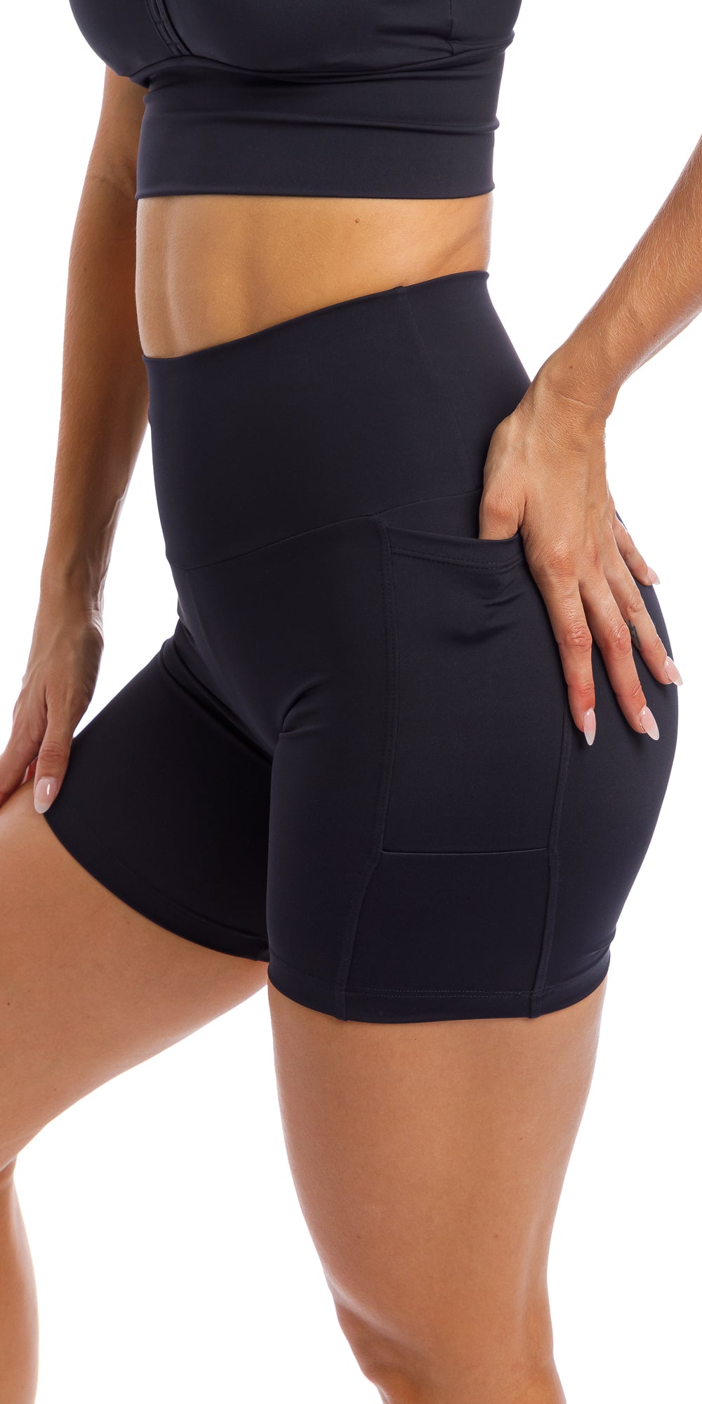 Girl putting hand in pocket of midnight body luxe midi shorts with pockets & matching racer bra