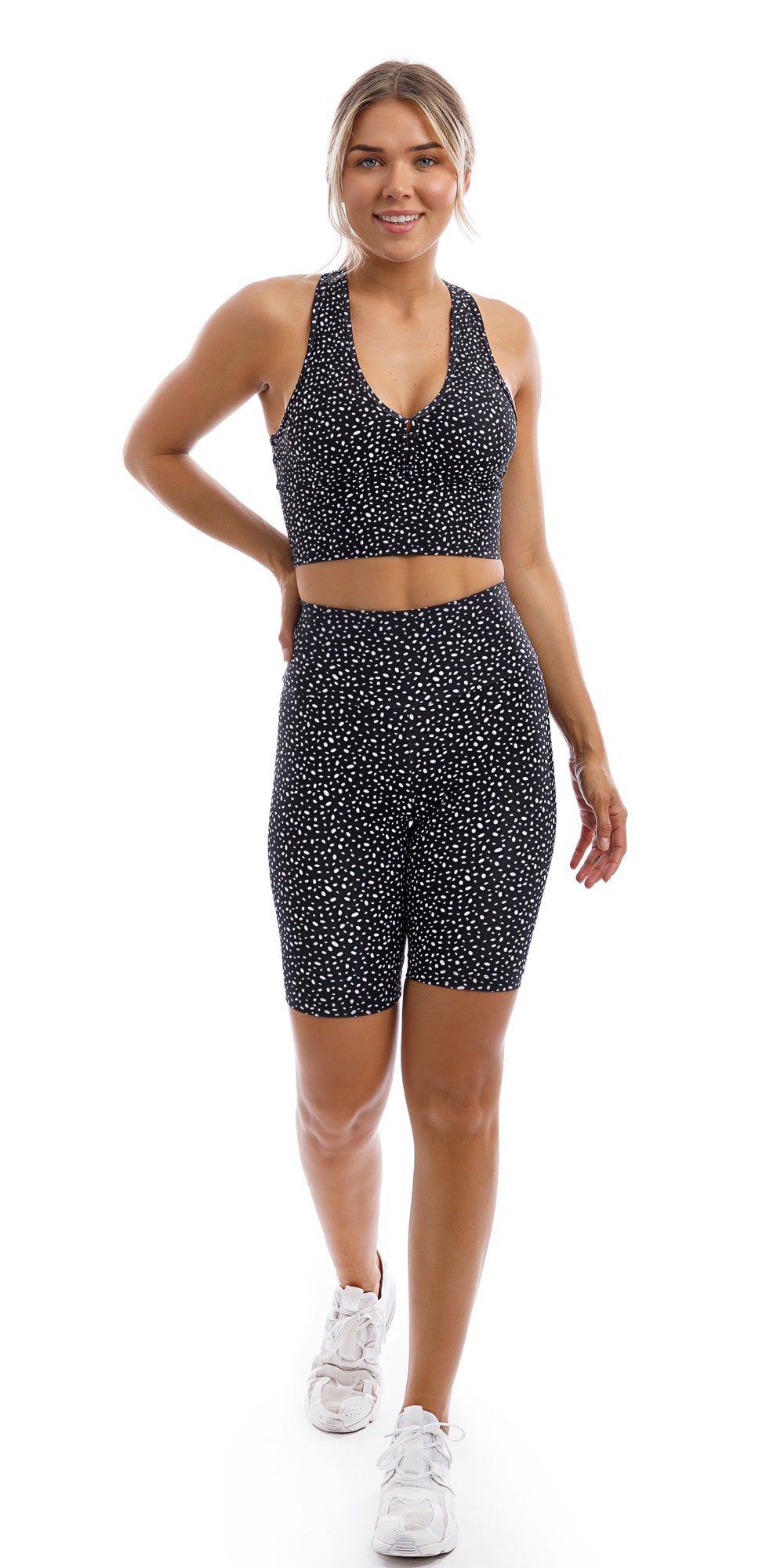 Full body front view of girl in black Star Dust Body Luxe Biker Shorts and matching bra putting one hand behind while walking