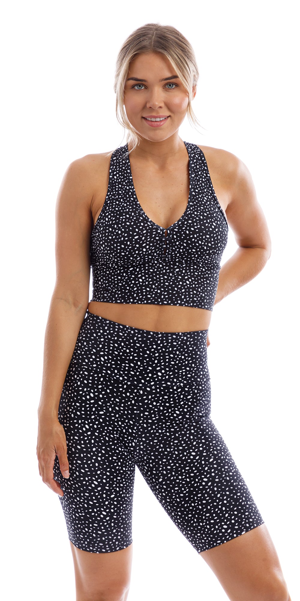 Front view of girl in black Star Dust Body Luxe Biker Shorts and matching bra putting one hand behind and one leg to the side