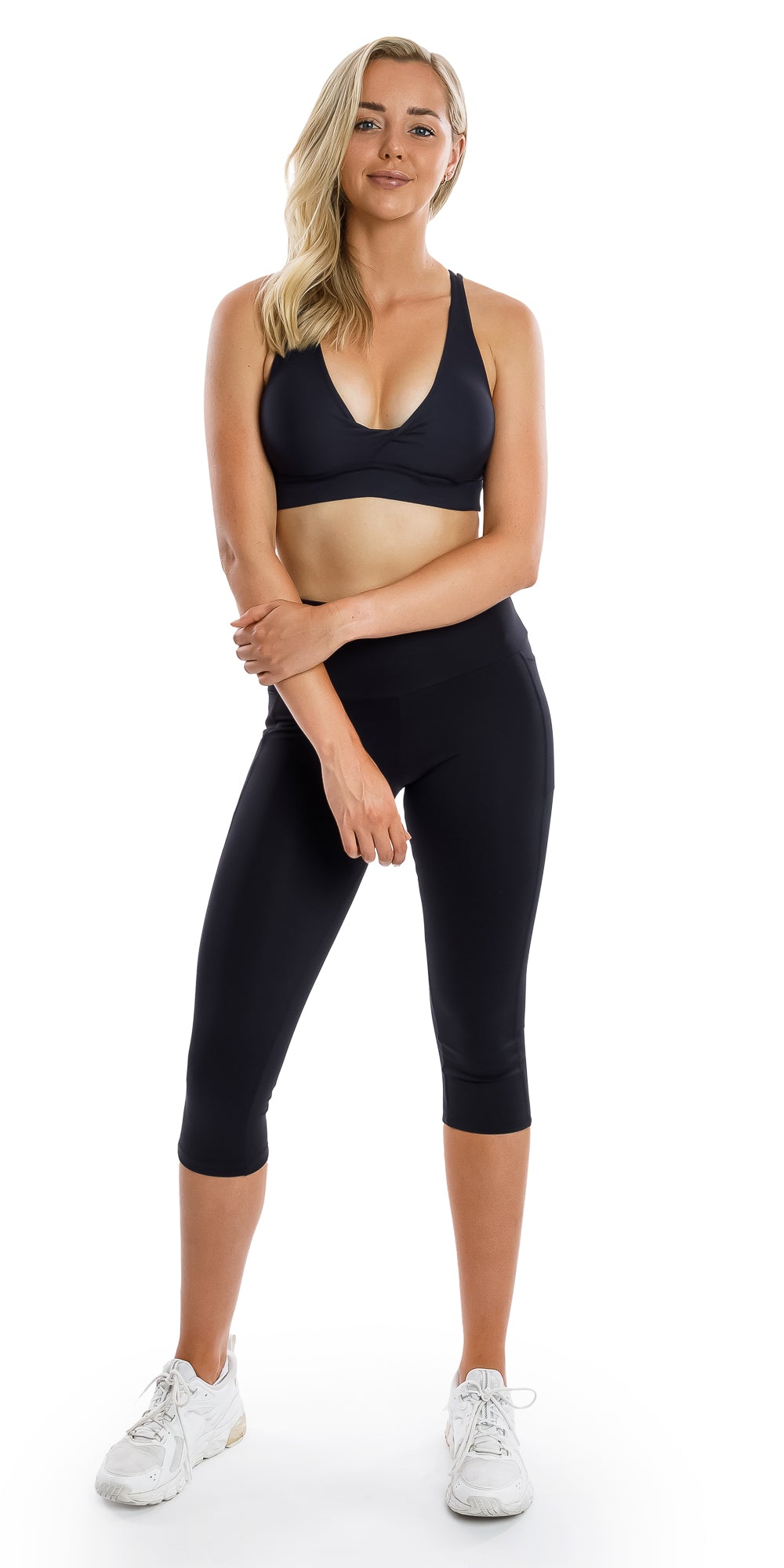 Full body front view of girl in black Midnight Eco Diamond Back Bra and matching bottoms holding right arm with left hand