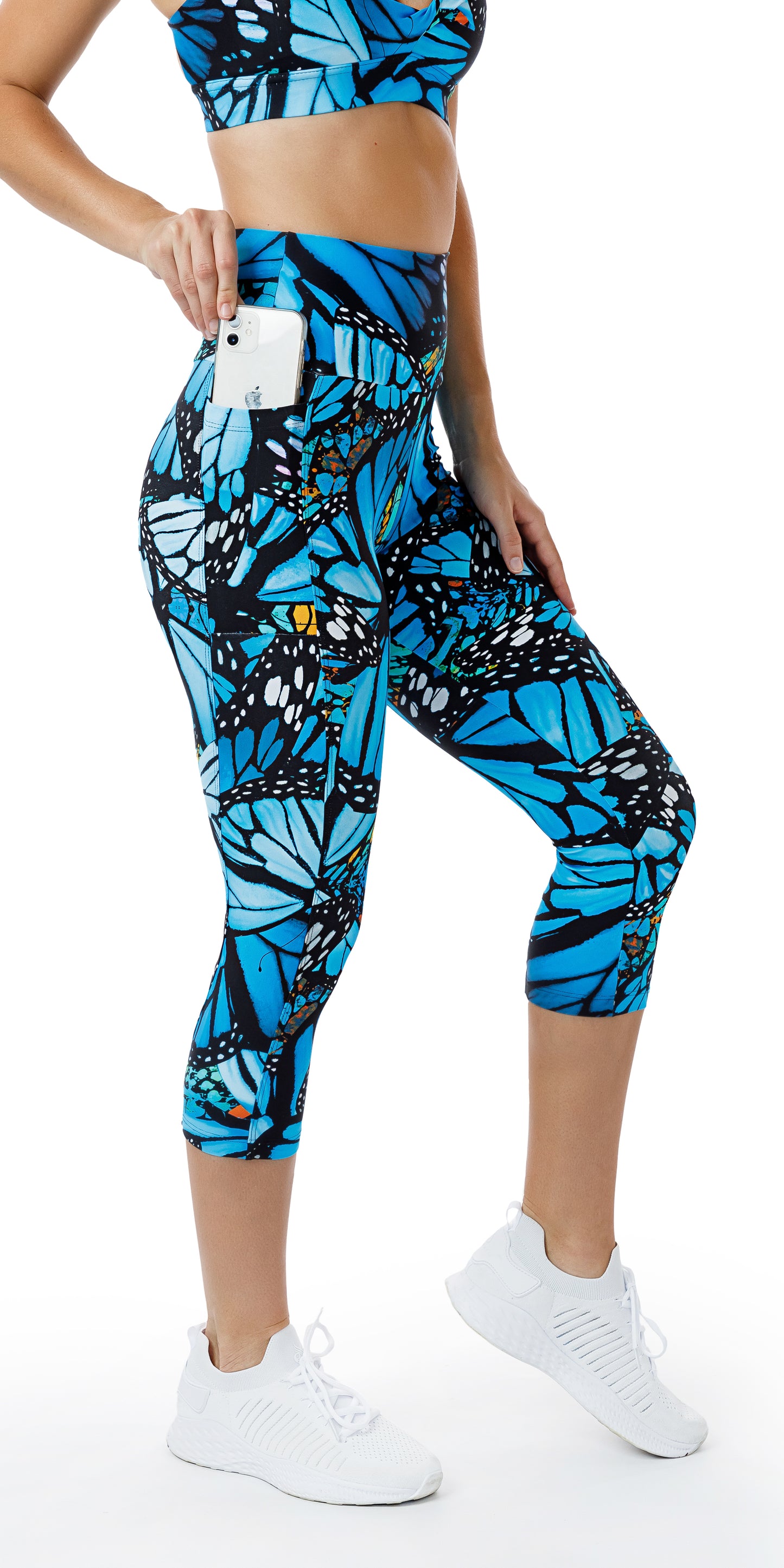 Side view of girl in blue animal print JH Butterfly Eco Capri Leggings with Pockets putting phone in the pocket