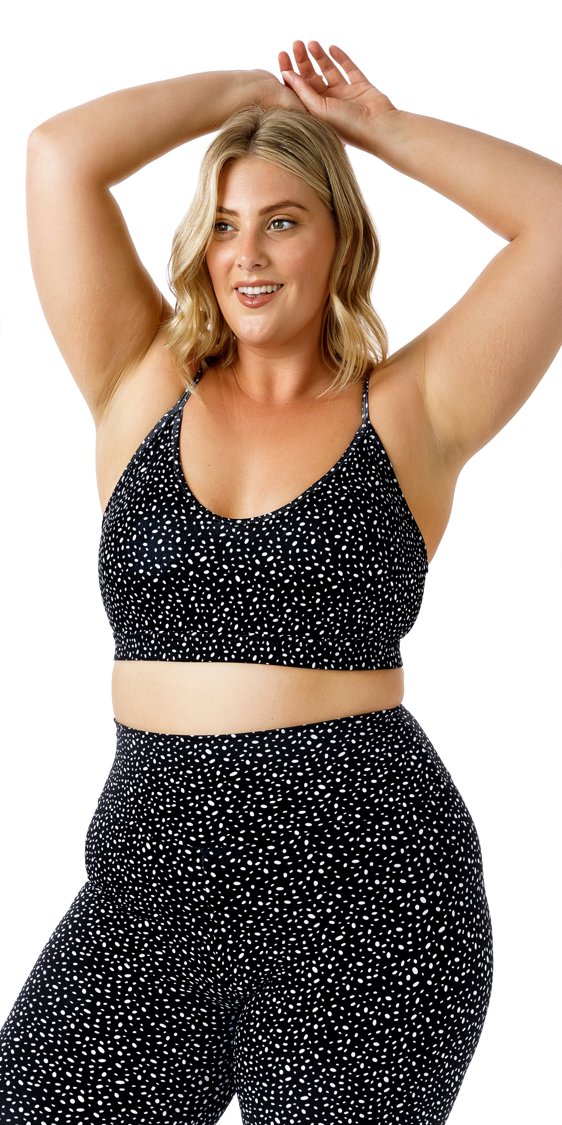 Front view of lady in black Star Dust Momentum Bra and matching bottoms raising both arms over head