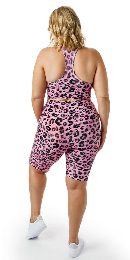 Full body side view of girl wearing pink animal print Candy Leopard Eco Biker Shorts with Pockets and matching racer back bra