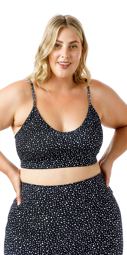 Front view of lady in black Star Dust Momentum Bra and matching bottoms smiling while putting both hands on waist