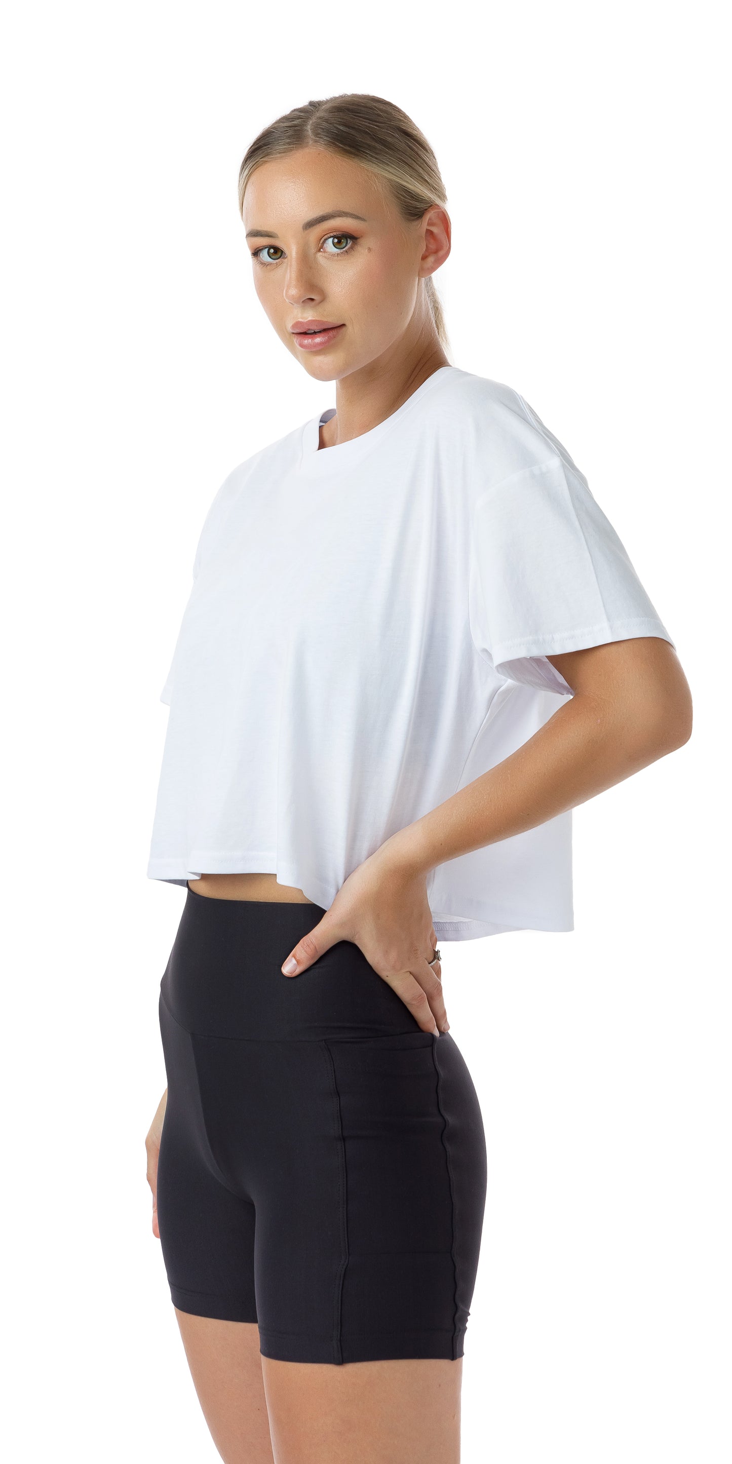 Side view of lady in White CL Active Crop Tee and black shorts putting both hands on waist