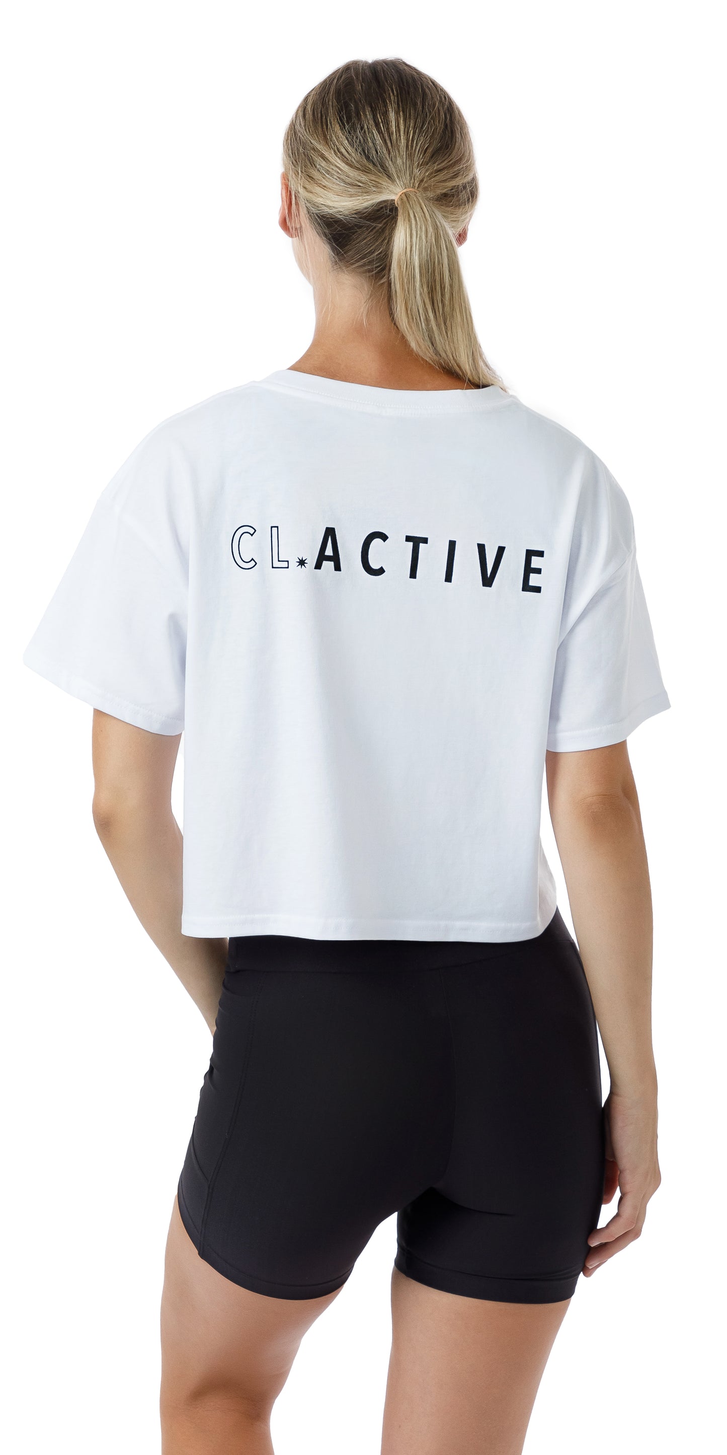 Back view of lady in White CL Active Crop Tee and black shorts lifting left knee and putting left hand on lap