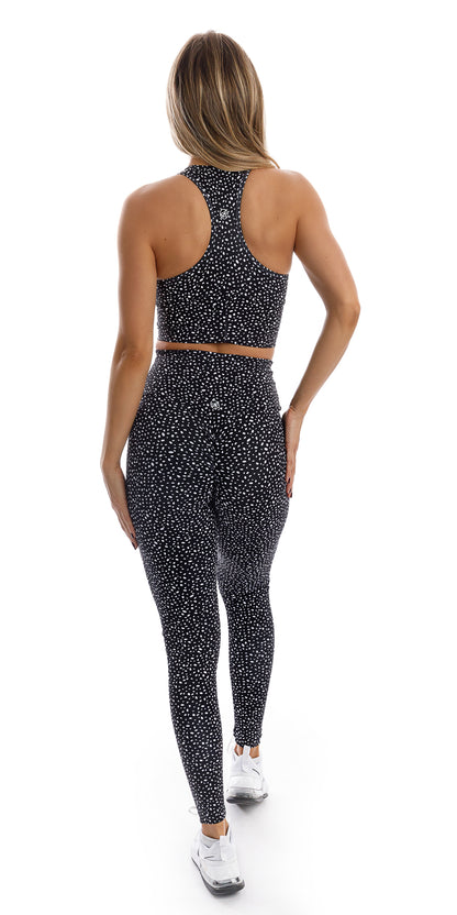 Full body rear view of girl in black Star Dust Body Luxe Scrunch Bum Leggings and matching racer back bra putting right leg forward and both hands on the sides