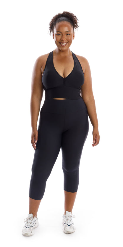 Full body front view of girl in black Midnight Body Luxe Capri Leggings with Pockets and matching bra