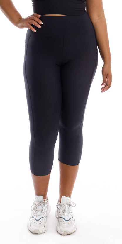 Front view of girl in black Midnight Body Luxe Capri Leggings with Pockets putting one hand on waist