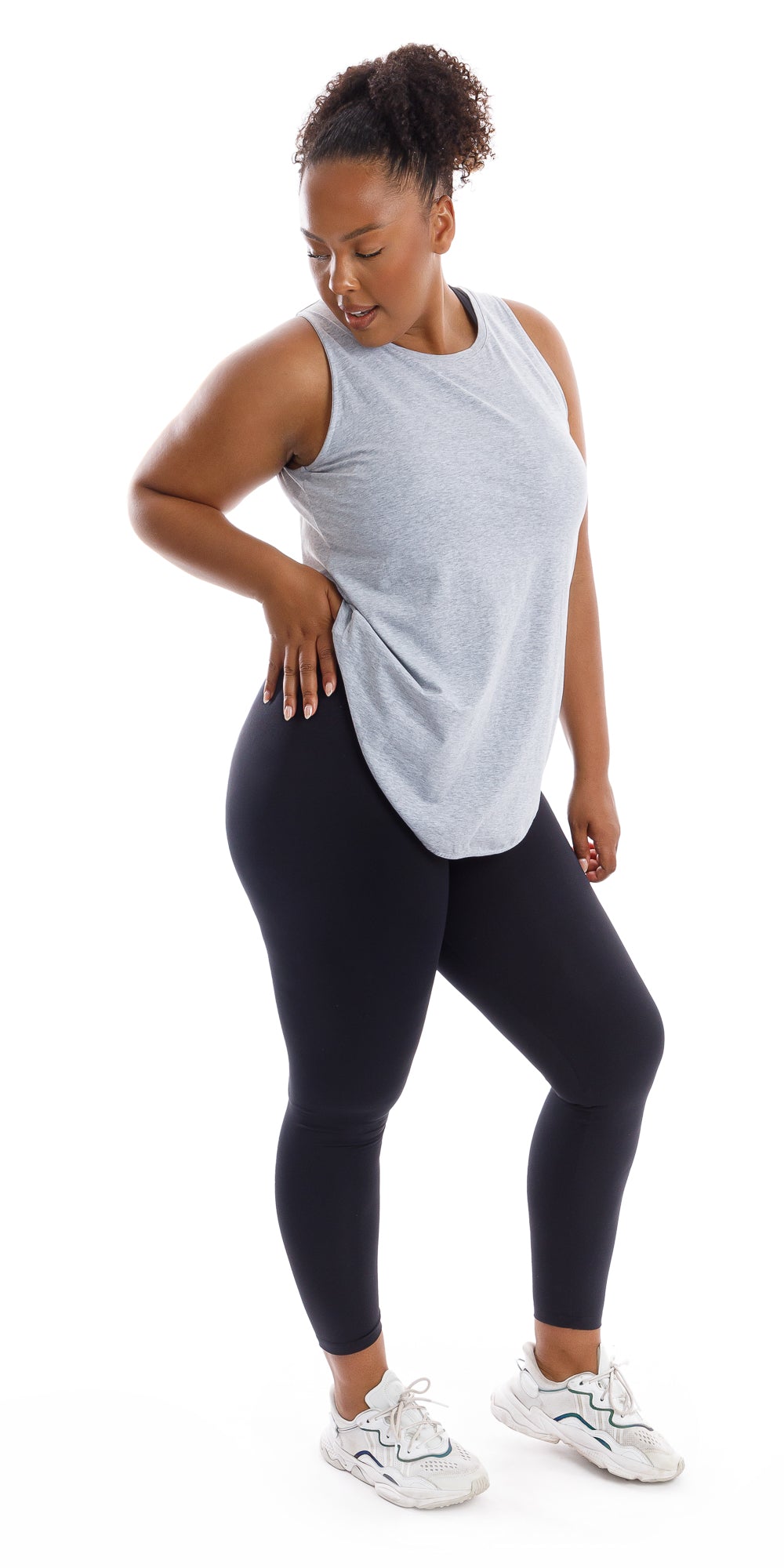 Full body side view of girl in Grey Palm Beach Tank and black leggings with one hand on waist