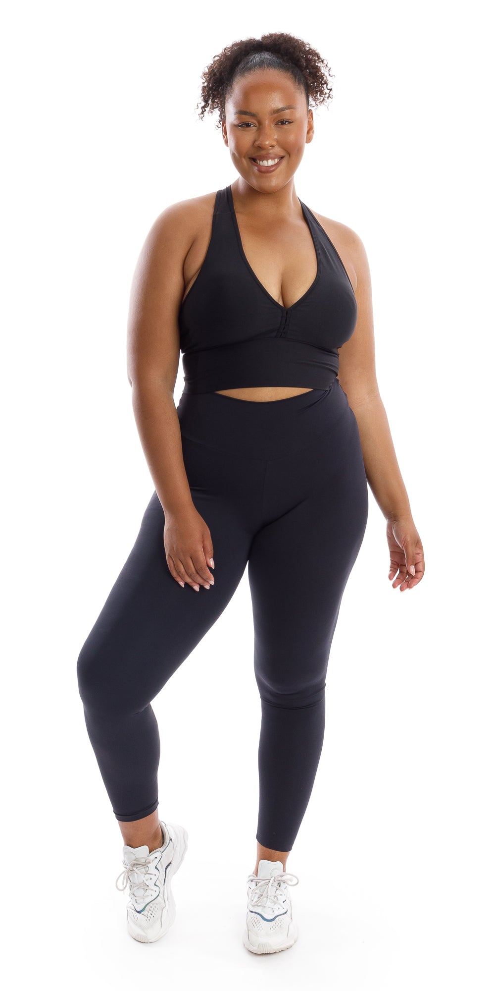 Full body front view of girl in black Midnight Body Luxe Scrunch Bum Leggings and matching bra lifting one heel to her right