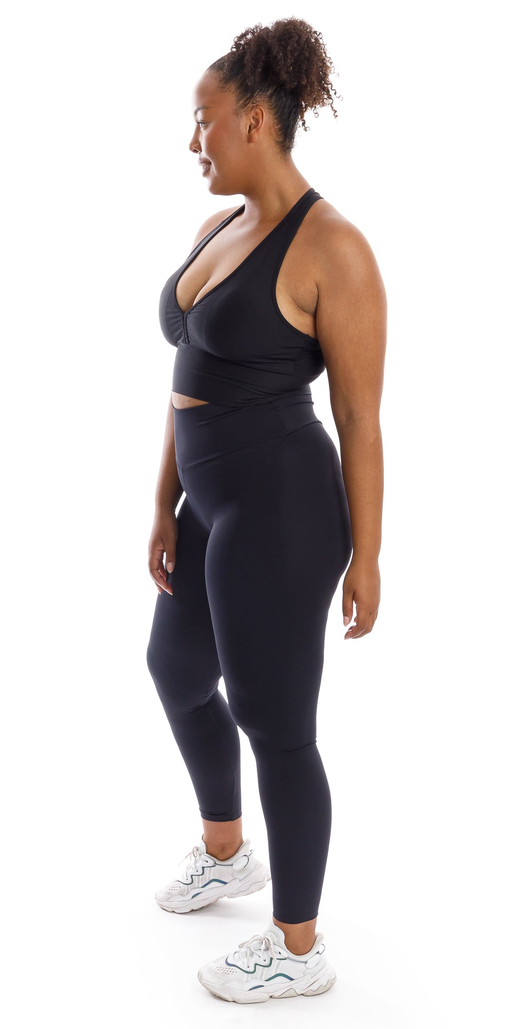 Full body side view of girl in black Midnight Body Luxe Scrunch Bum Leggings and matching bra looking to her right