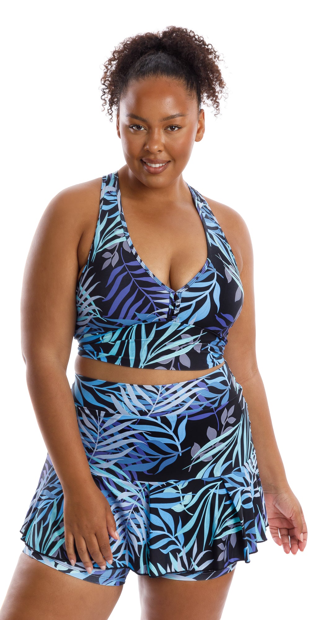 Front view of lady in black and blue Tropical Palm Skort with Pockets and matching bra putting one hand on lap while looking straight to the camera