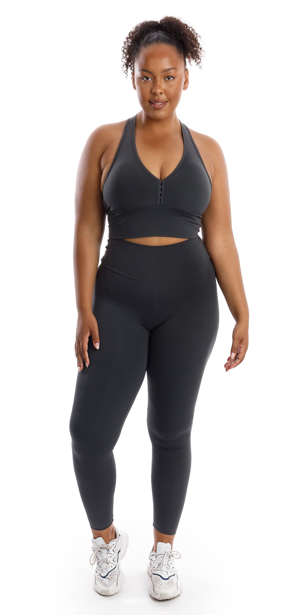 Full body front view of girl wearing grey Liquorice Body Luxe Scrunch Bum Leggings and matching racer back bra lifting one heel