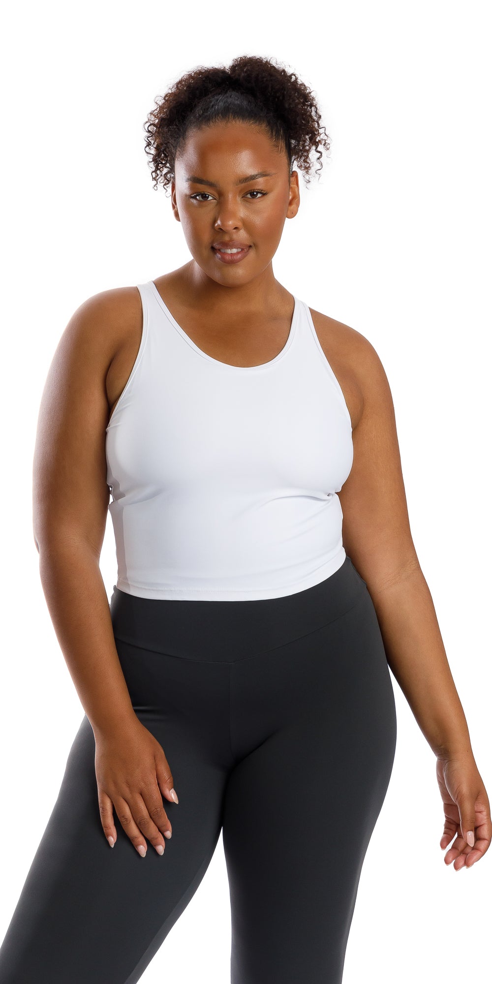 Front view of lady in sleeveless White Crop Top and black leggings putting right hand on lap
