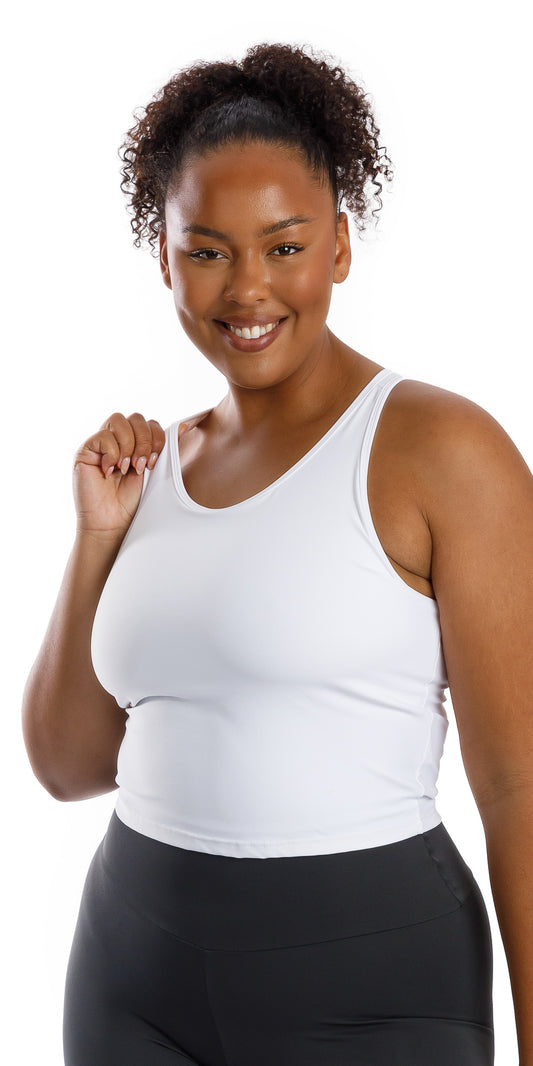 Front view of lady in sleeveless White Crop Top holding the right strap and smiling