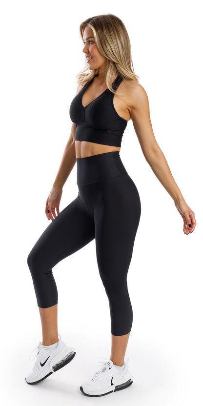Full body side view of girl in black Midnight Eco Capri Leggings and matching bra lifting one heel and swaying arms