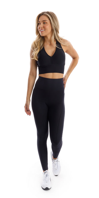 Full body front view of girl wearing black Midnight Eco Ultra High Waist Leggings with Pockets and matching bra walking