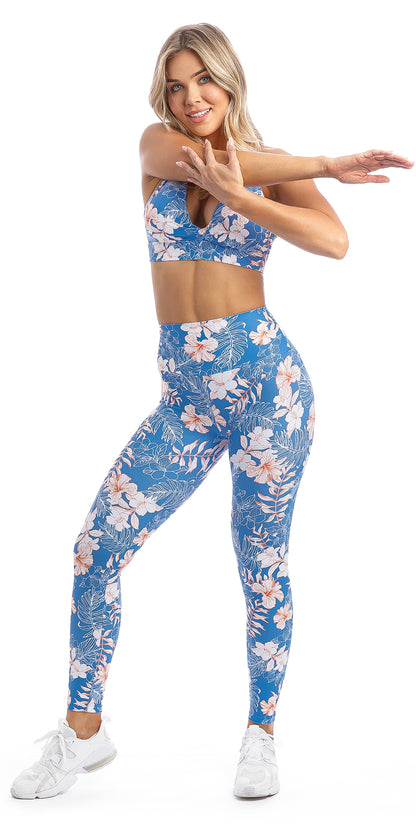 Lady stretching her arm wearing blue, white, pink floral Hibiscus Kiss print ultra high waist leggings & matching infinity bra