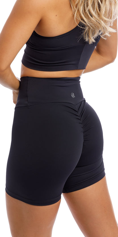 Rear view of girl wearing midnight body luxe scrunch bum midi shorts & matching racer bra 