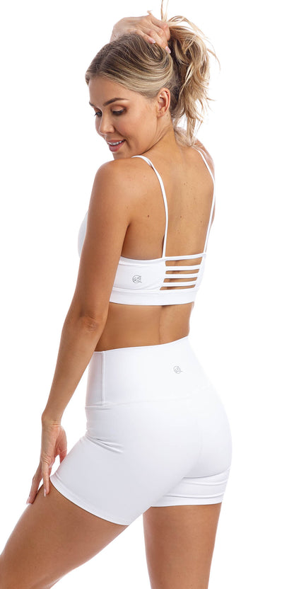 Rear view of girl wearing white momentum bra with three horizontal back straps & matching white lined midi shorts