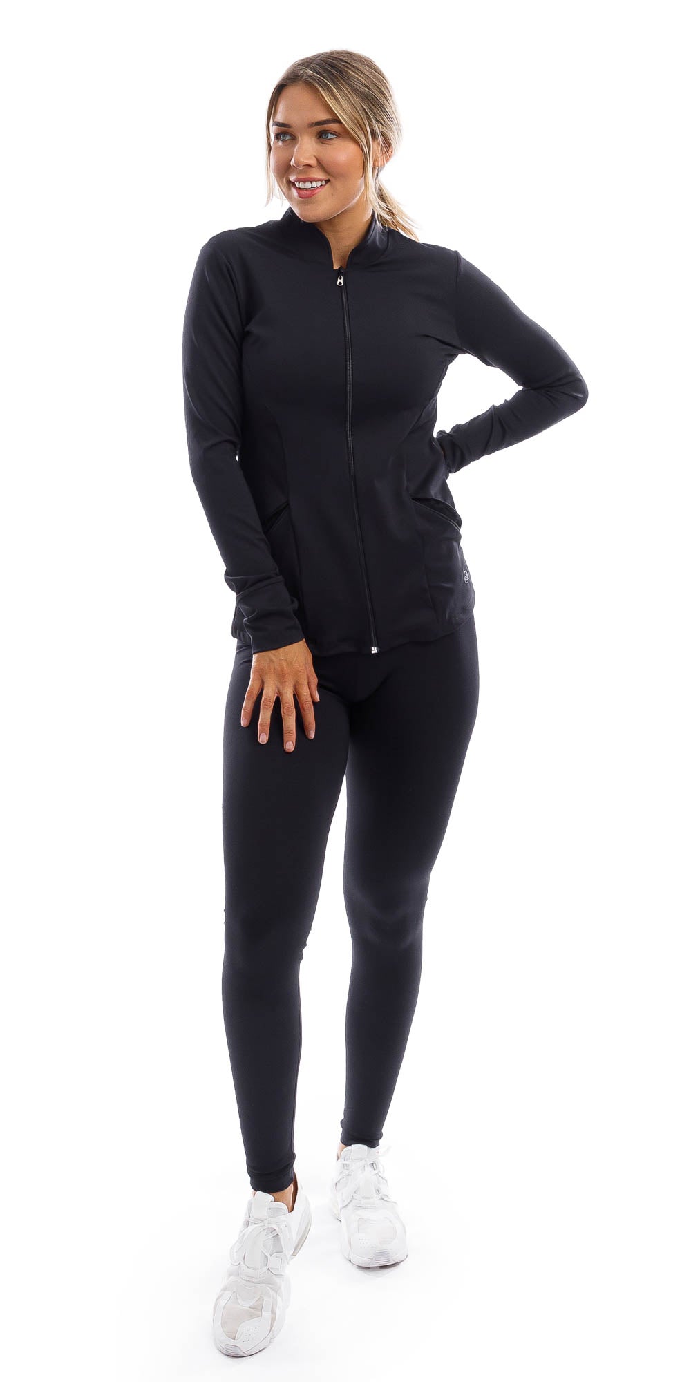Girl standing in black midnight endurance jacket with zip and thumb pockets & midnight leggings