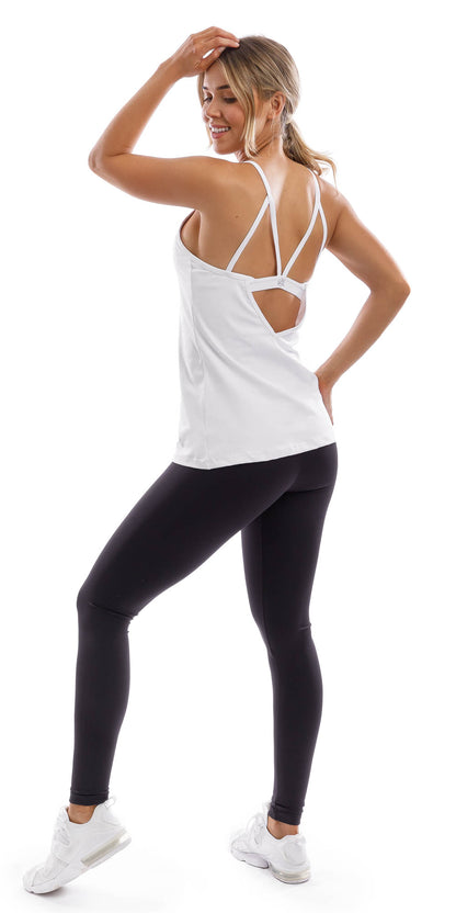 Full body angled side view of lady in strappy White Performance Tank and black leggings putting left leg forward and left hand on head while putting right hand on waist
