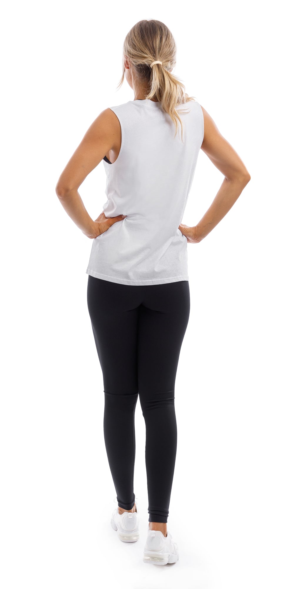 Full body rear view of lady in White CL Active Tank and black leggings walking and putting both hands on waist
