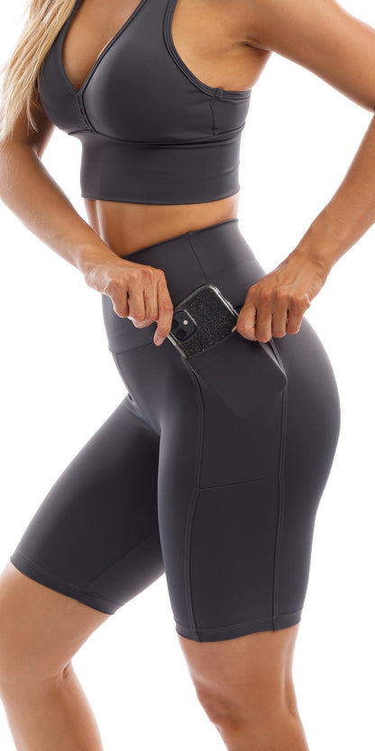 Girl putting phone in side pocket of Liquorice body luxe biker shorts with pockets & matching racer back bra
