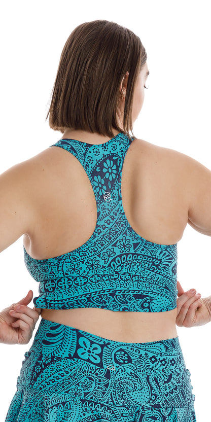 Rear view of girl in aqua blue Paisley Tide Eco Racer Back Bra and matching skort touching the end of the bra