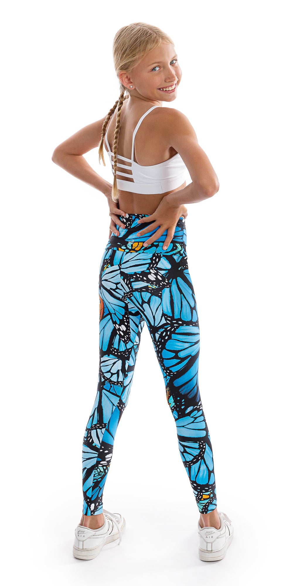 Full body back view of girl teenager in blue and black animal print Tween JH Butterfly Ultra High Waist 7/8 Leggings standing with feet apart and putting both hands on waist while looking back to smile for the camera