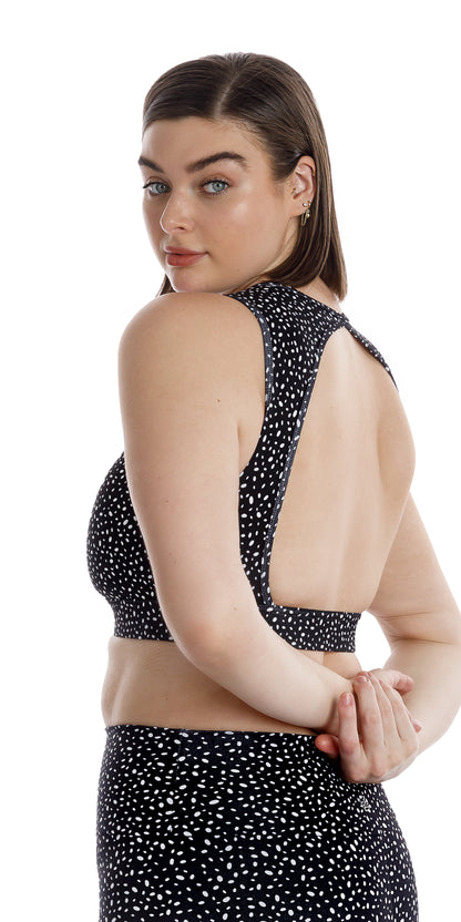 Angled side view of lady in black Star Dust Rhythm Bra looking straight to the camera while putting both arms behind