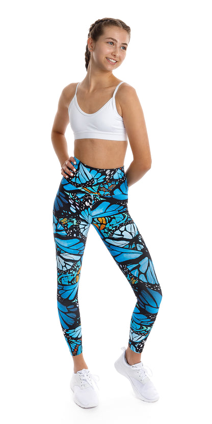 Full body front view of girl teenager in blue and black animal print Tween JH Butterfly Ultra High Waist 7/8 Leggings and white bra leaning on one leg while lifting left heel and putting one hand on waist and the other behind her back