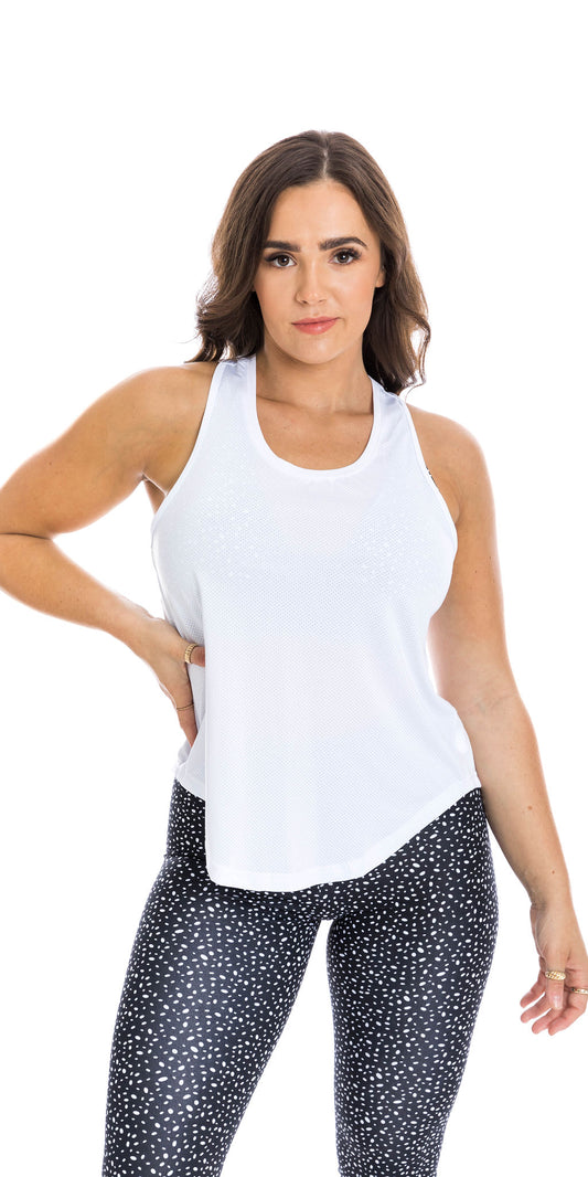 Front view of lady in sleeveless White Meshed Racer Back Tank and black dotted leggings putting right hand on waist